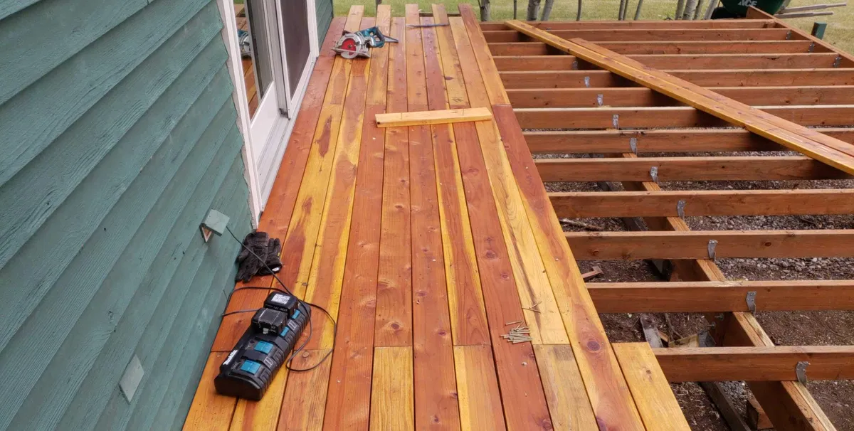 Cedar deck construction showing joist framing and partial decking on residential home